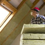 Man installing thermal roof insulation layer – using mineral woo